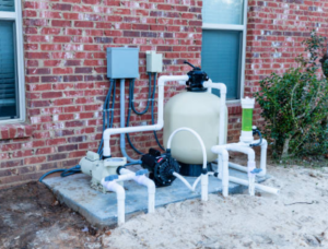 Image of pool pump and filter equipment installed next to a brick home wall