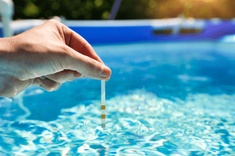 Image of hand holding pool chemistry test strip